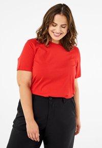 Raudoni trumpomis rankovėmis marškinėliai iš minkštos medvilnės, su apvalia kaklo linija. Derinami su laisvais juodos spalvos kelnėmis. Paprastas dizainas, be raštų.