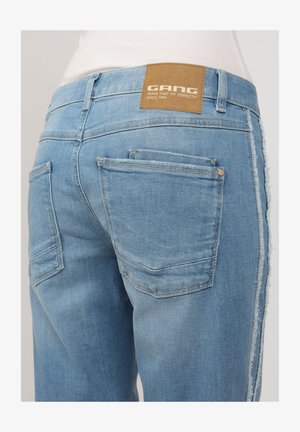 Light blue denim jeans featuring a leather tag reading "GANG," five pockets, a distressed hem, and a slim fit design.