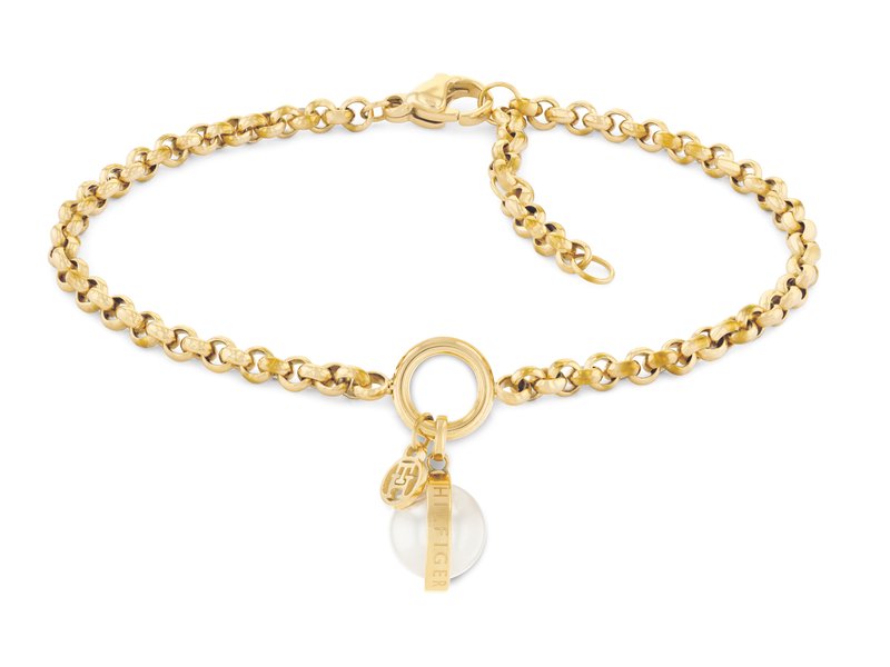 Pulsera de cadena de metal en tono dorado con un anillo circular y un charm, que presenta una piedra blanca y una etiqueta con el nombre de la marca. Enlaces texturizados, cierre ajustable.