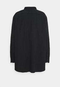 Camisa negra de manga larga con cuello tipo solapa, con puños abotonados y corte recto. Tela lisa sin patrones visibles.