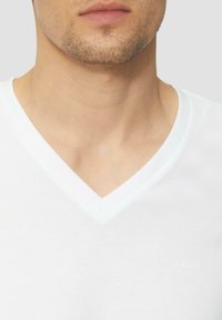 Biała bawełniana koszulka z dekoltem w kształcie v, charakteryzująca się miękką teksturą i dyskretnym logo s.Oliver w jasnym ścieg na klatce piersiowej.