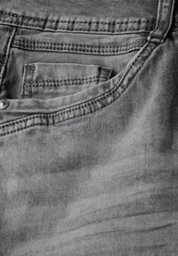 Tessuto denim grigio con una tasca dai bordi cuciti, leggere variazioni di texture e un accento in metallo sul bottone in vita.
