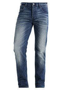 Jeans de denim para hombre en azul oscuro con parches desgastados, corte recto, diseño clásico de cinco bolsillos y acento de botón de metal en la cintura.