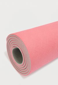 Ροζ στρώμα γιόγκα τυλιγμένο με υφή στην επιφάνεια και γκρι πίσω πλευρά, με ομόκεντρους κύκλους στα άκρα.