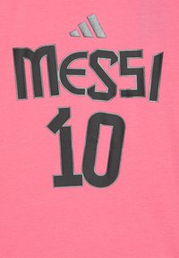 Rozā T-krekls ar melnu, lielu tekstu "MESSI" un numuru "10". Izstrādāts ar mīkstu tekstūru un brīvu piegriezumu.