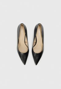 Zapatos de tacón negro de cuero con puntera afilada, de textura suave y diseño bajo, con plantilla beige y el interior de marca "Calvin Klein".