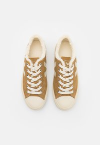 Brown suede sneakers featuring a soft cream lining, beige rubber toe caps, and contrasting white laces with logo details on the sides.