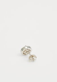 Boucle d'oreille en argent avec un design circulaire, surface texturée et un dos en métal. Présente une tige pour un maintien sécurisé.