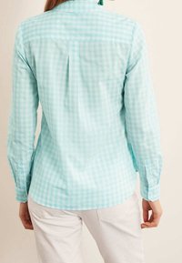 Light blue gingham button-up shirt with long sleeves, featuring a collar and a yoke back. Material appears smooth and textured.