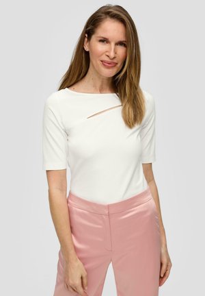 Haut blanc à manches courtes avec un large décolleté et un détail en découpe diagonale. Associé à un pantalon en satin rose clair, à texture lisse et à coupe ajustée.