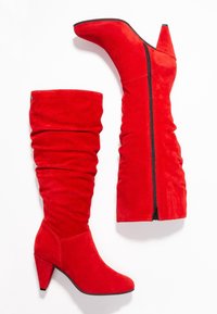 Bottes montantes en daim rouge avec un design décontracté, bout pointu et talon conique de 4 pouces ; fermeture à glissière latérale.
