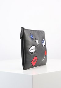 Czarna skórzana sakiewka z kolorowymi haftowanymi detalami: niebieskie gwiazdy, oczy, czerwone usta oraz dymek z napisem "meow!". Zapięcie na suwak.
