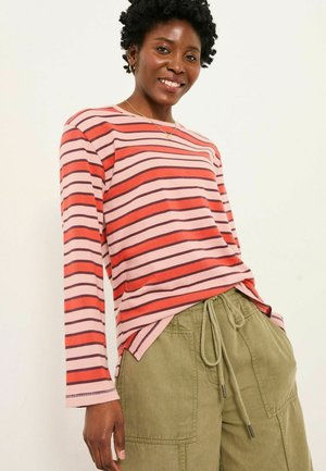 Gestreiftes Langarmshirt in Rosa- und Rottönen mit Rippstruktur, kombiniert mit khakifarbenen, oversized Hosen mit Kordelzug.