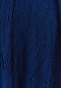 Getextureerde blauwe stof met een golvend patroon, die een zachte, lichte kwaliteit vertoont. Het oppervlak heeft verticale rimpelingen en diepte.