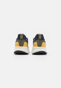 Men's sneakers featuring a navy upper, yellow and olive accents, textured material, and a white speckled midsole with a black outsole.