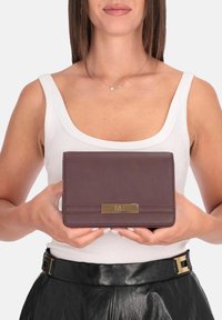 Pochette in pelle marrone scuro con finitura testurizzata, forma rettangolare e dettaglio in metallo color oro sul davanti.