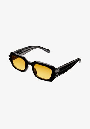 Lunettes de soleil noires surdimensionnées avec des lentilles jaunes carrées, dotées de montures angulaires épaisses et de détails en bandes sur les branches.