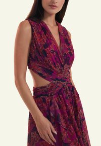 Plunge-neck dress in purple with floral patterns. Features pleated fabric and an open side design. Lightweight material with flowing texture.