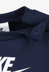 Μπλε ναυτικό βαμβακερό φούτερ με στρογγυλή λαιμόκοψη, με κουμπιά τύπ ου snap στον ώμο και έντονη λευκή εκτύπωση λογότυπου Nike.