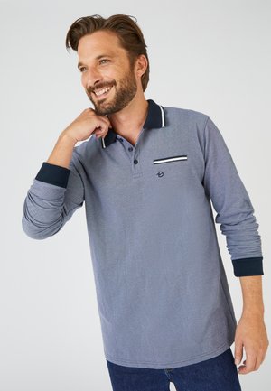Polo de manga larga en gris con acentos en azul marino, que cuenta con un cuello, tapeta de botones y un detalle de bolsillo con rayas horizontales.