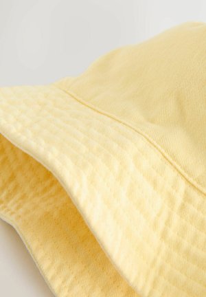 Żółty kapelusz typu bucket wykonany z fakturowanej tkaniny, z szerokim rondem i szwem na koronie. Miękki, lekki wygląd z delikatnym wzorem.