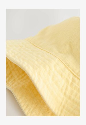 Žlutý klobouk typu bucket vyrobený z texturované látky, s širokou krempou a švem na vrcholu. Měkký, lehký vzhled s jemným vzorem.