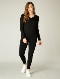 Zwarte lange mouw top met V-hals en aansluitende zwarte leggings. Draag het met witte sneakers, wat zorgt voor een slanke, gestroomlijnde silhouette en een gladde textuur.