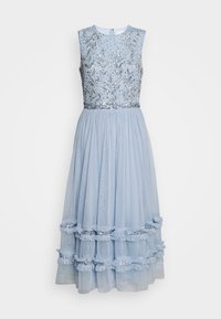Robe bleu clair avec un design sans manches, corsage orné de sequins argentés et de motifs de feuilles, et jupe à volants superposés.