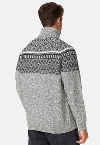 Grauer Strickpullover mit hohem Kragen, der ein schwarz-weißes geometrisches Muster an den Schultern und am Rücken aufweist. Strukturierter Stoff.