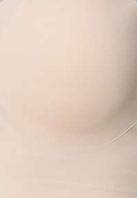 Beige sømløs bh med en glatt, ribbet tekstur og formeede kopper, uten synlige sømmer for et elegant utseende.