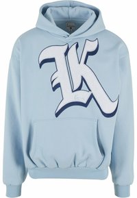Light blue hoodie with a large white and navy embroidered “K” logo, kangaroo pocket, ribbed cuffs, and waistband. Soft fabric texture.