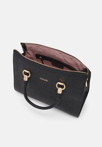 Fekete kézitáska bemart mintával, arany alkatrészekkel és dupla fogantyúkkal. Belseje rózsaszín bélésű, logónyomattal. Cipzáros zárás.