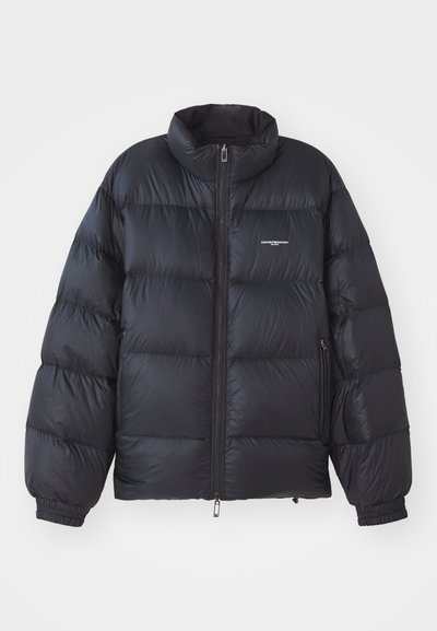 Black puffer jacket featuring a high collar, zip closure, elastic cuffs, and a logo on the chest. Smooth, shiny material with a padded design.