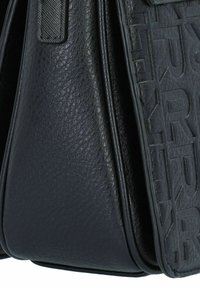 Zwarte leren handtas met een textuur en gegraveerd merklogo. Kenmerkende hoekige vorm met contrasterende gladde en getextureerde panelen.