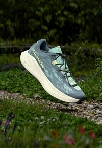 Αθλητικό ελαφρύ παπούτσι με πράσινο πλεκτό επάνω μέρος με σχεδιασμό μοτίβου, μαύρα κορδόνια και λευκή σόλα με υφή πάτου.