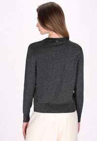 Maglione pullover nero a maniche lunghe con una leggera lucentezza. Maglia testurizzata e dettaglio a coste sull'orlo. Scollo rotondo semplice, branding minimale.