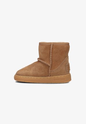 Bruine suède enkelboot met een ronde neus, eenvoudige stiksels, elastische bovenrand en een gestructureerde rubberen zool. Logo gedrukt aan de zijkant.
