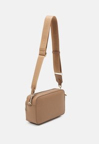 Brązowa prostokątna torba na ramię o gładkiej fakturze, złotych akcentach i regulowanym pasku z logo. Zamek błyskawiczny z przodu.