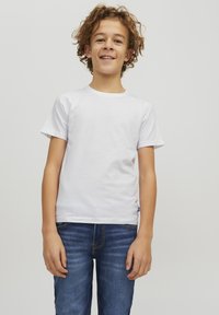 T-shirt bianco a maniche corte in cotone, con scollatura rotonda. Indossato con jeans di denim blu, che mostrano una vestibilità comoda e una leggera scoloritura.
