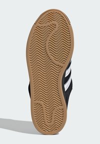 Čierna podrážka tenisky so štruktúrovaným vlnitým vzorom; materiál z gumovej gumy. Na boku sú tri biele pruhy pre dodatočný detail.