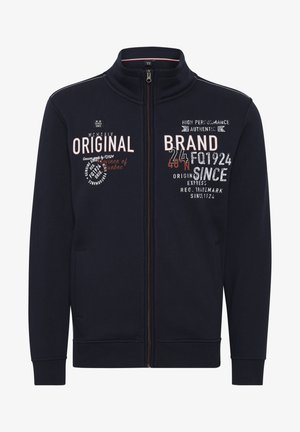 Chaqueta de cremallera en color navy, fabricada con tela suave, con un alto cuello, dos bolsillos laterales y detalles de texto impreso en varios colores en la parte delantera.