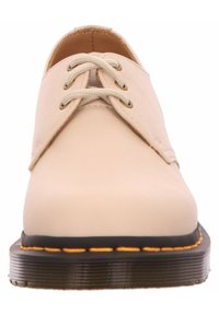 Beige Schnürschuhe mit einem glatten Lederobermaterial, runder Zehenpartie und kontrastierender schwarzer und gelber Gummisohle mit strukturierten Akzenten.