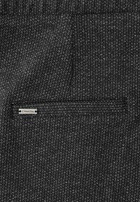 Zwart-wit textiel met een subtiele breipatroon, voorzien van een kleine, rechthoekige zak en een 'Street One' label.