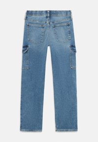 Jeans din denim de colorare albastru deschis, cu un brâu elastic, două buzunare pe spate și buzunare laterale pentru cargo. Materialul are o textură uniformă, ușor estompată.