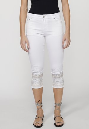 Weiße Capri-Jeans mit dekorativer Stickerei und Strasssteinen an den Säumen, ausgestattet mit Fronttaschen und einem silbernen Knopfverschluss.
