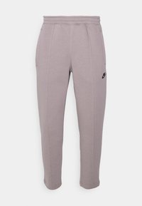 Pantalones de chándal gris claro hechos de una tela suave, con pierna ajustada, banda elástica en la cintura, bolsillos laterales y un logo negro en el muslo.