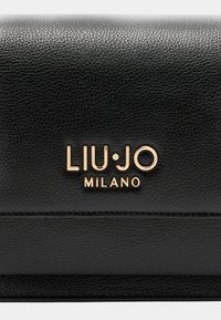 Černá kožená peněženka s texturovaným povrchem, která má na přední straně výrazně zobrazené zlaté logo "LIU·JO MILANO".