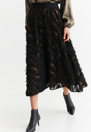 Sort midi-nederdel med tekstureret frynset zebra-mønster, båret med sorte ankelstøvler og en metallisk langærmet top.