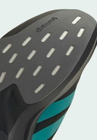 Black and teal athletic shoe sole featuring a textured surface, cutouts for grip, and a Continental logo embossed on the side.