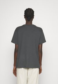 T-shirt en coton gris à manches courtes et col ras du cou, avec une coupe décontractée et une texture lisse. Aucun logo ou motif visible.